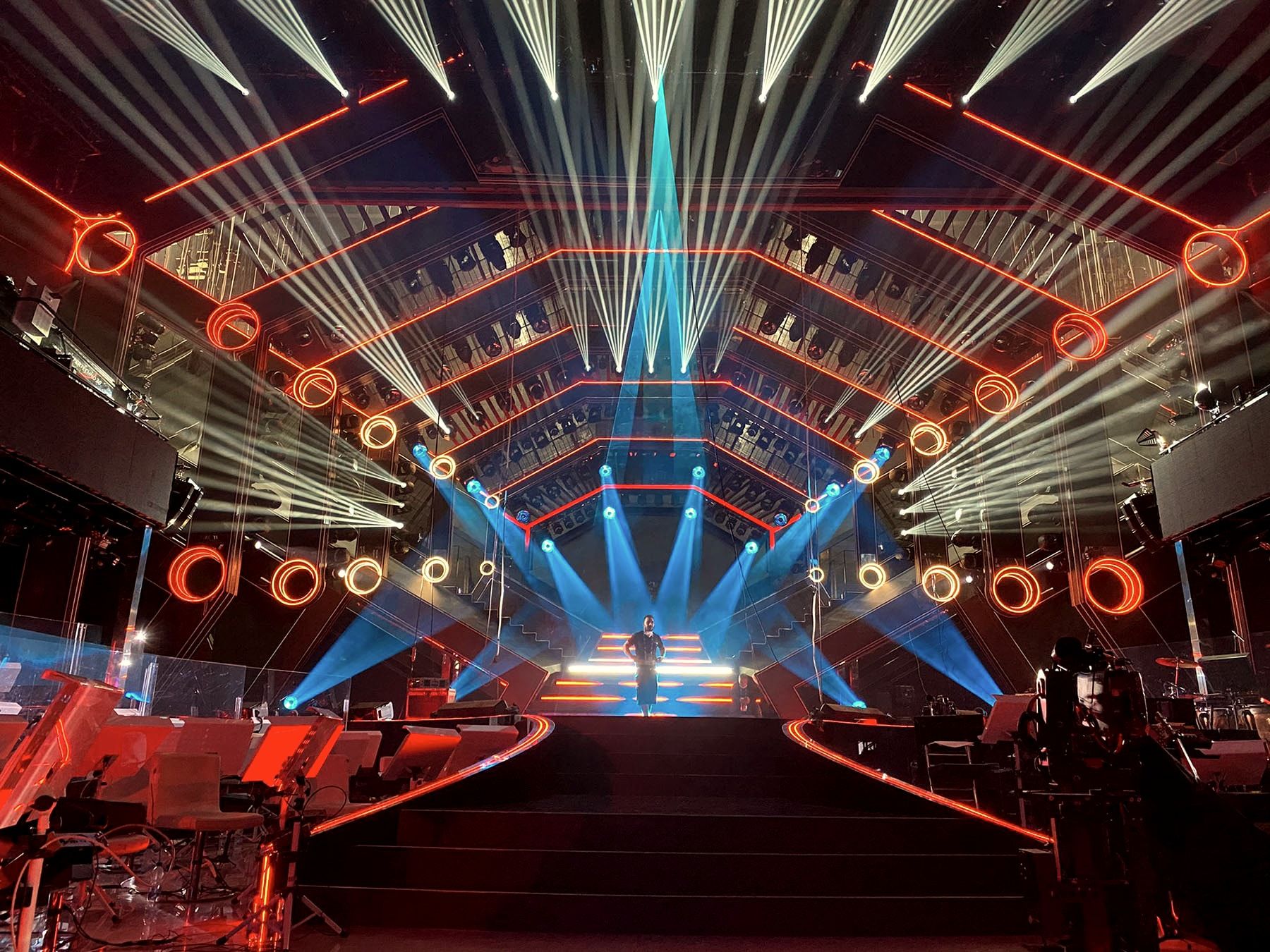 Il rig luci del Teatro Ariston durante le prove del Festival di Sanremo 2021: fasci bianchi e blu sopra il palco vuoto.